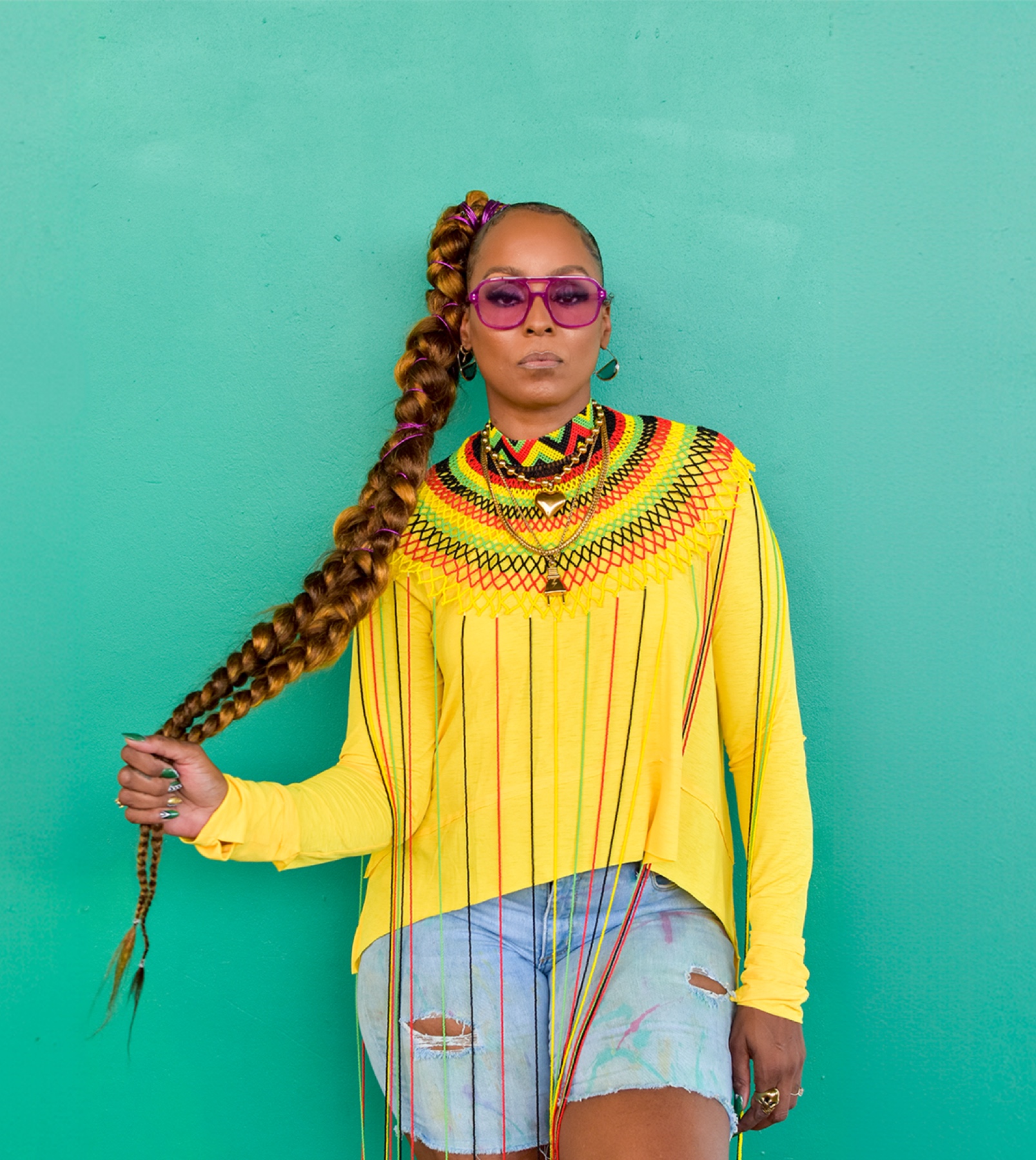 Angela Hunte in yellow against a turquoise wall